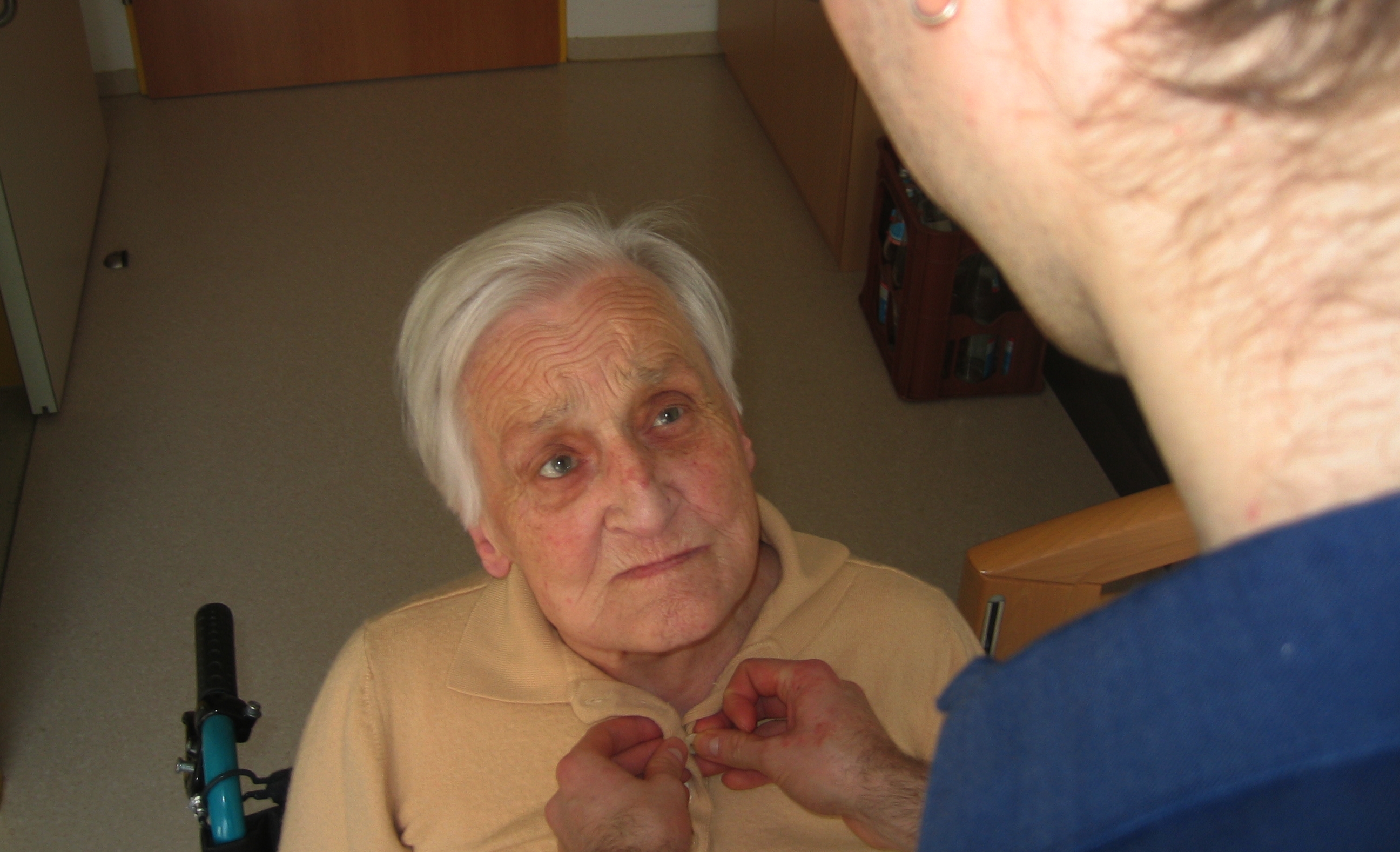 Senior wird von Pfleger angezogen