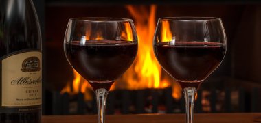 Red wine glasses in front of a fire