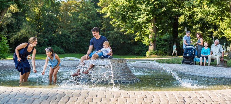 Familie spielt am Brunnen