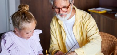 cute little girl and senior granddad painting with colorful paints at home