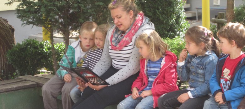 Eine Tagesmutter ließt des Kindern vor.