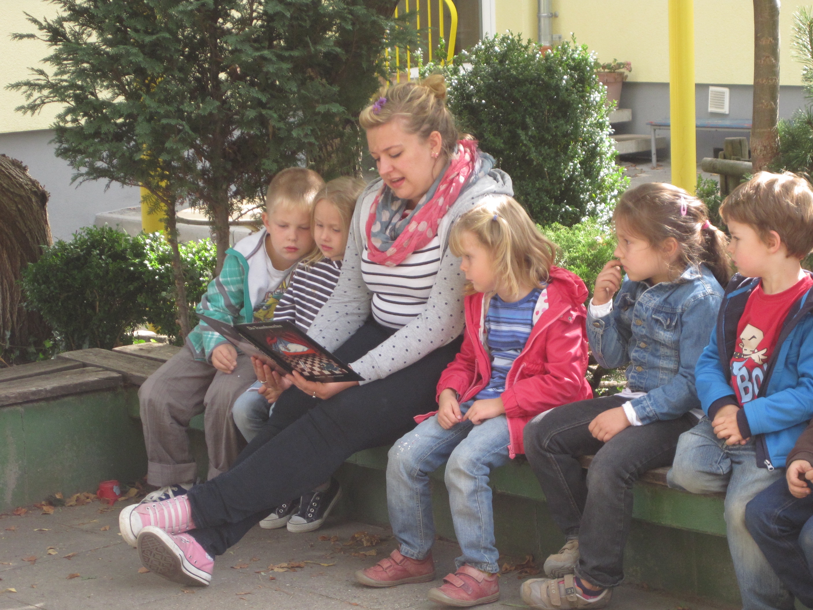 Eine Tagesmutter liest Kindern vor.