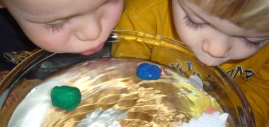 Kinder lassen Knete und Stiropor auf Wasser treiben