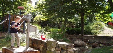 Ein Kind pumpt an der Matschanlage