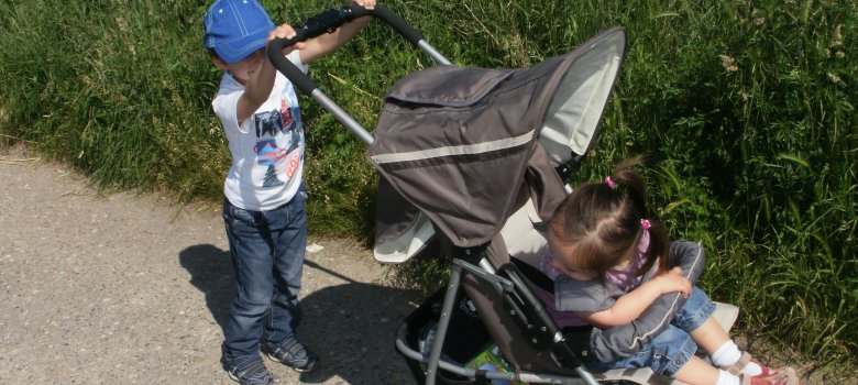 Ein Kind schiebt einen Kinderwagen