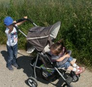 Ein Kind schiebt einen Kinderwagen