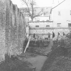 Umgebung der Mikwe, hier links die Außenwand der Synagoge. Der Durchbruch hinten links ist der ehemalige Zugang zu dem Areal. Aufgenommen wahrscheinlich Mitte 1998 im Rahmen einer Begehung im Zuge von Ausgrabungen.