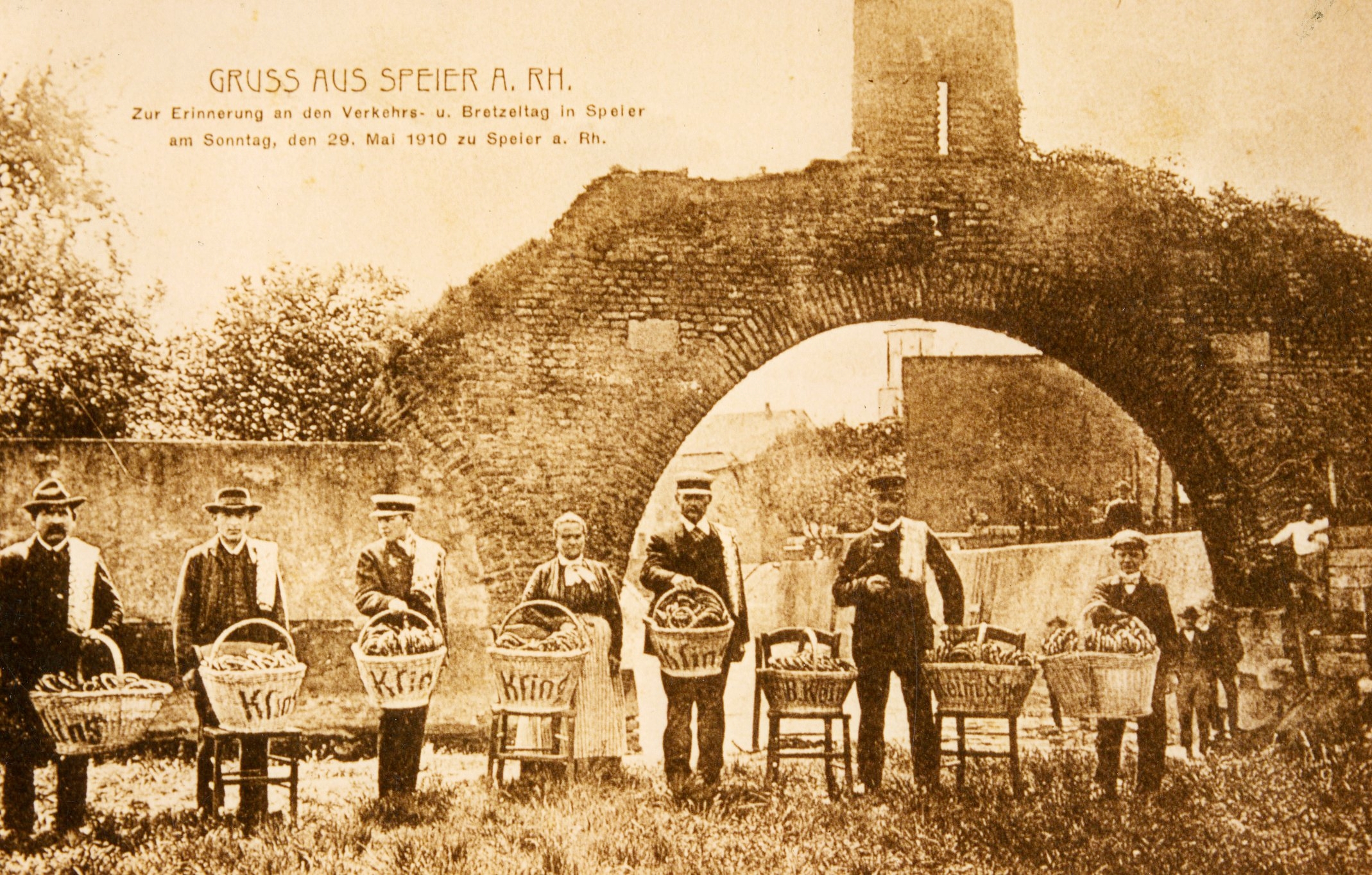 Erinnerungskarte vom ersten Brezelfest 1910 mit Brezelverkäuferinnen und - verkäufern der Speyerer Bäckereien Kling und Keim, versammelt vor dem „Riegel“, der alten Stadtmauer am nördlichen Rand der Speyerer Altstadt. 