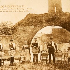 Erinnerungskarte vom ersten Brezelfest 1910 mit Brezelverkäuferinnen und - verkäufern der Speyerer Bäckereien Kling und Keim, versammelt vor dem „Riegel“, der alten Stadtmauer am nördlichen Rand der Speyerer Altstadt. 