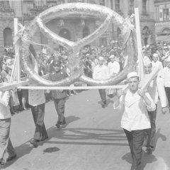 Die Speyerer Bäcker tragen beim Festumzug 1937 eine Riesenbrezel über den Postplatz. 