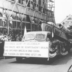 Ein Motivwagen der Speyerer Schiffswerft Braun durchquert die Gilgenstraße, vermutlich mit viel Gehupe und Getöse – denn das Mädchen ganz rechts hält sich die Ohren zu, 1955.