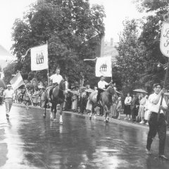 Der Festumzug 1957 ist verregnet. Die Fahnenträger zu Fuß und zu Pferd sind davon glücklicherweise wenig beeindruckt