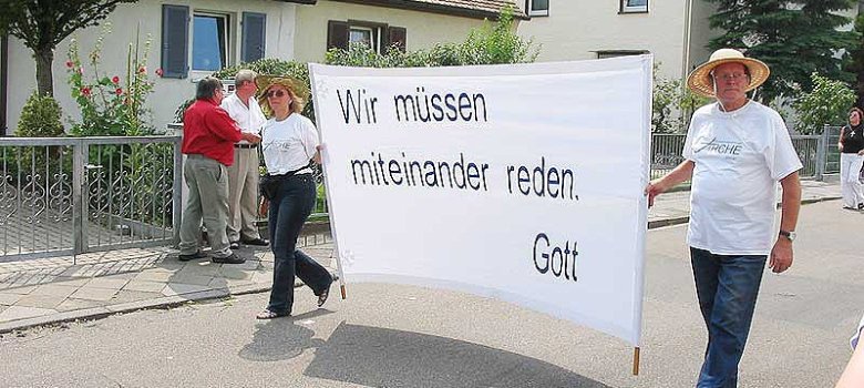 Mitglieder der Gemeinde mit Plakat "Wir müssen miteinander reden. Gott."