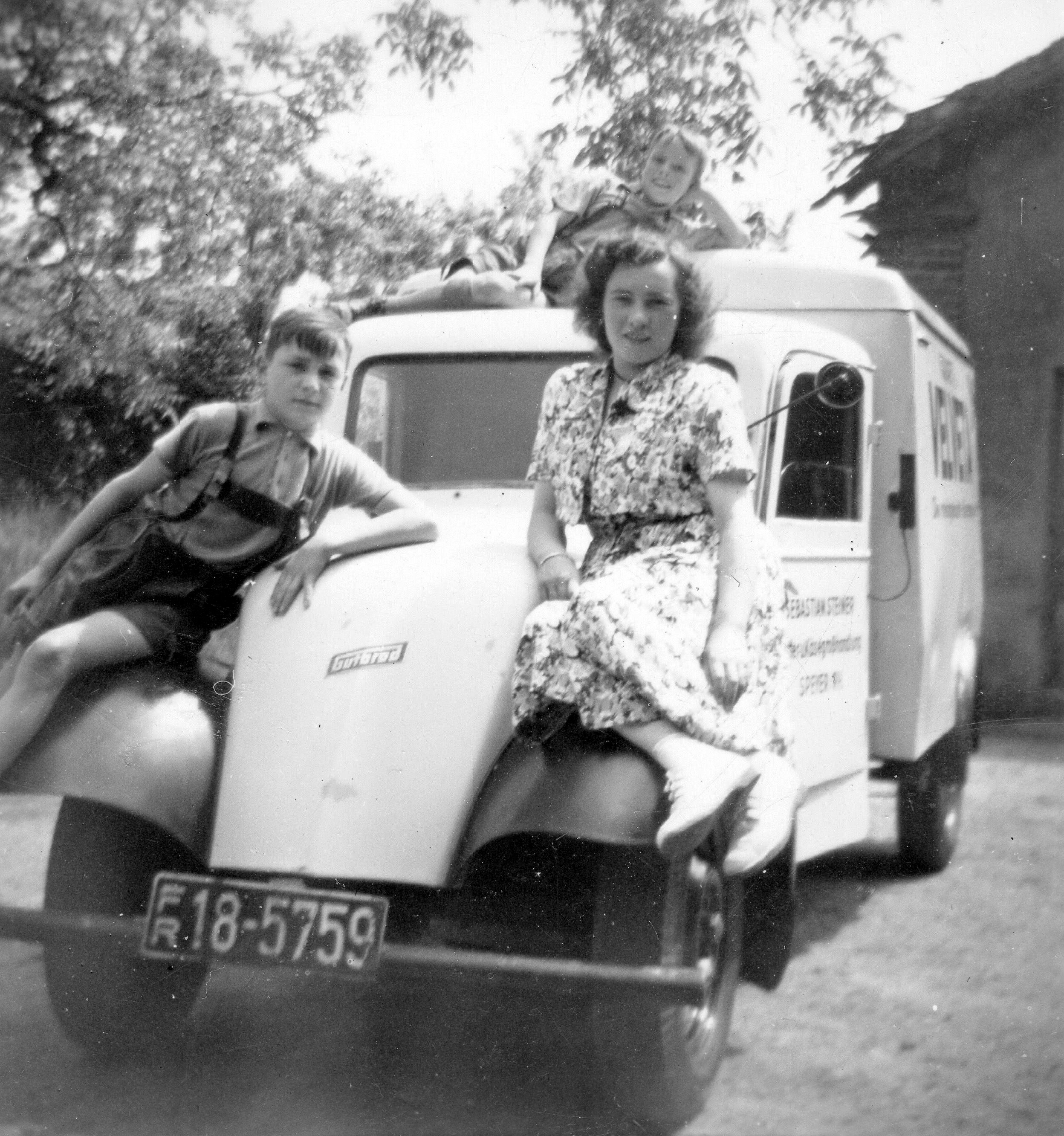 Frau mit Kindern auf Lieferfahrzeug der Nachkriegszeit