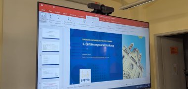 Ein digitales Board zeigt eine Power Point Präsentation mit Vorschau auf die erste Folie  "1. Einführungsveranstaltung"