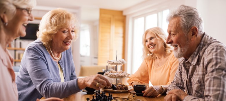 Happy senior people playing chess while relaxing at home.