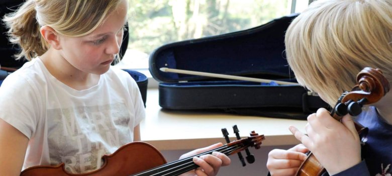 Zwei Kinder spielen Geige.