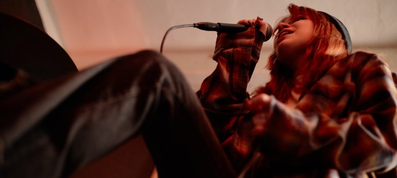 Emotional Teenage Girl Singing into Mic Performing Music with Rock Band in Studio