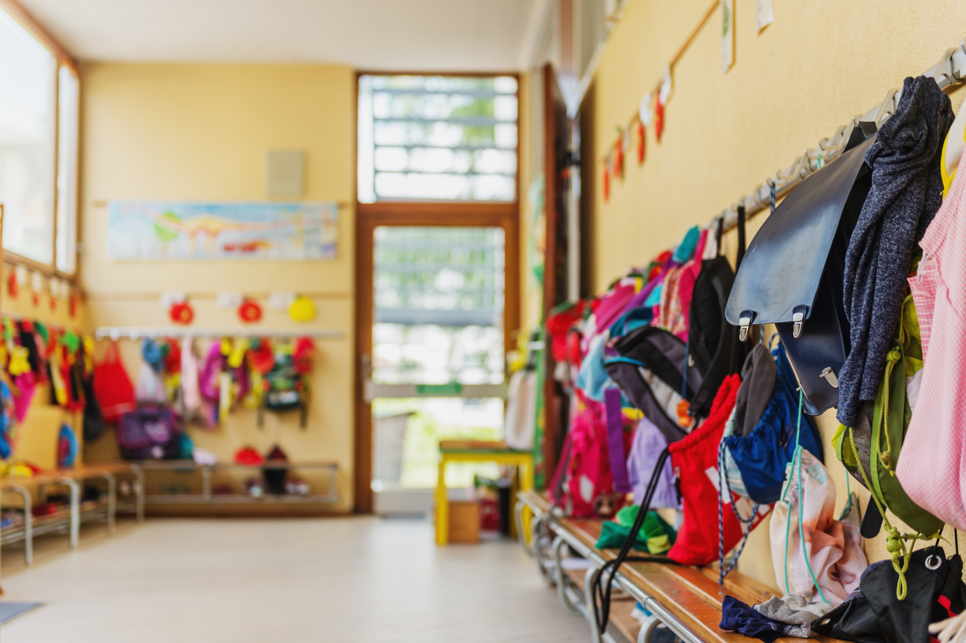 Blick in einen Kindergartenflur, an der Wand hängen viele bunte Jacken