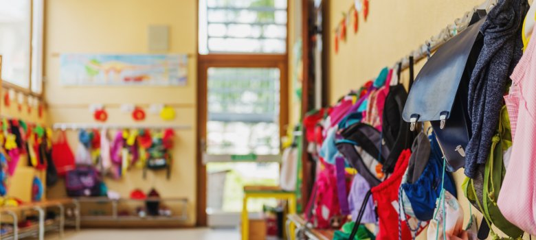 Blick in einen Kindergartenflur, an der Wand hängen viele bunte Jacken