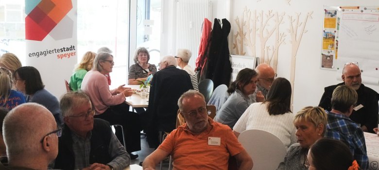 Eine Gruppe von Personen sitzt an verschiedenen Tischen und befindet sich beim Stammtisch Ehrenamt im Gespräch.