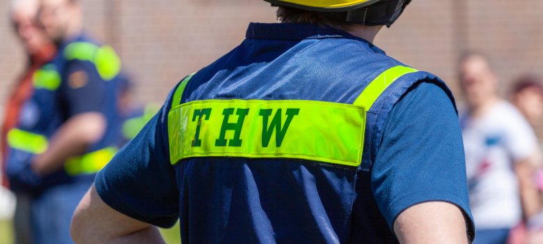 Deutsches Einsatzzeichen „THW“ auf der Warnweste eines Mannes. THW steht für „Technisches Hilfswerk“.