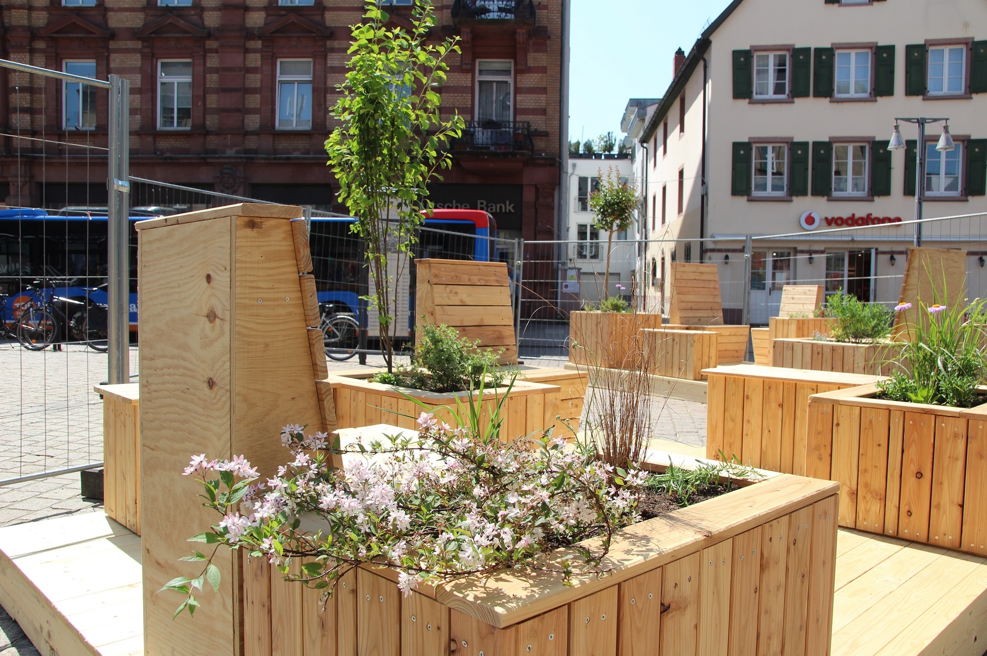 Sitzmöbel aus Holz mit bepflanzten Hochbeeten am Postplatz in Speyer