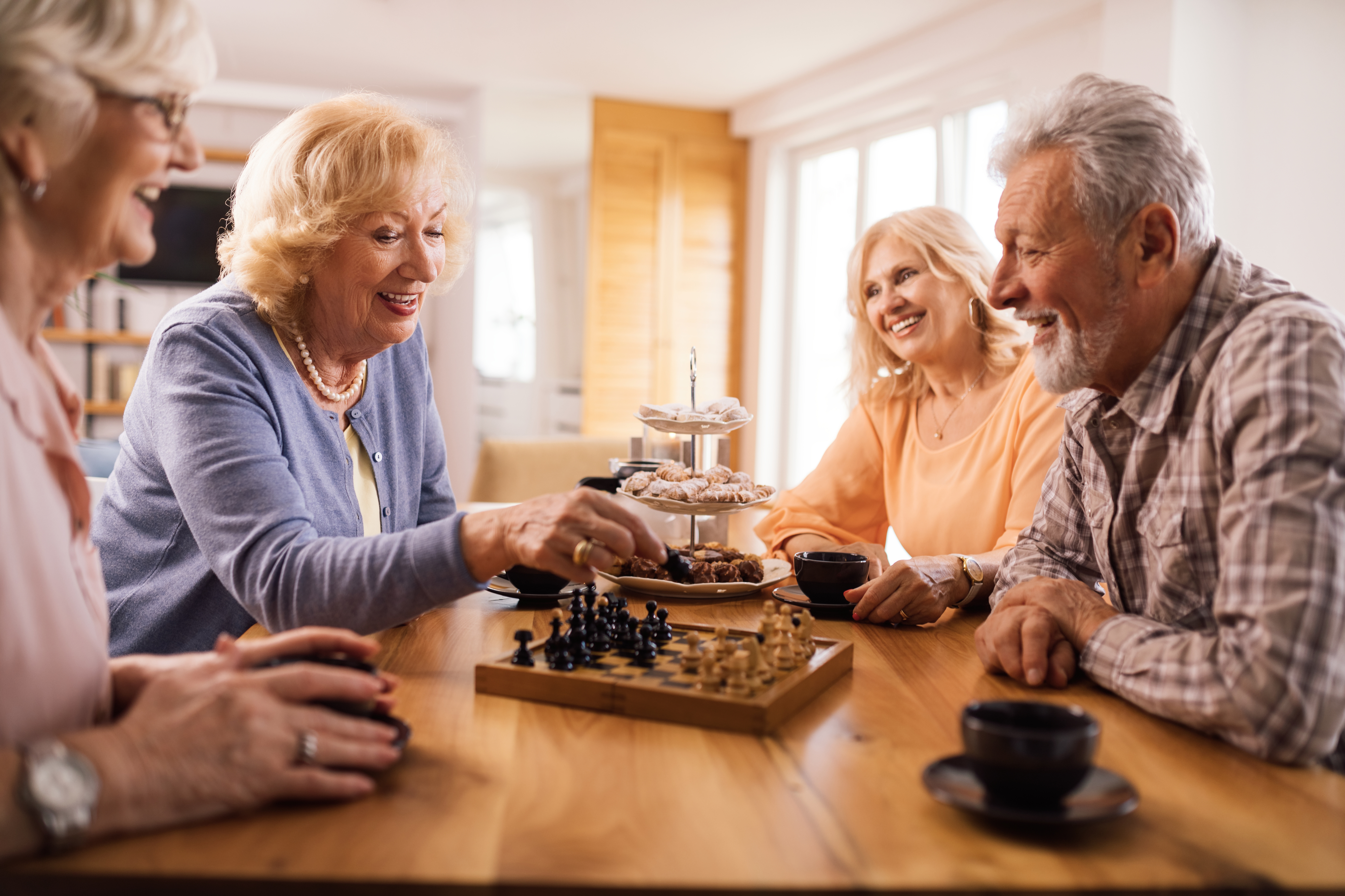 Happy senior people playing chess while relaxing at home.