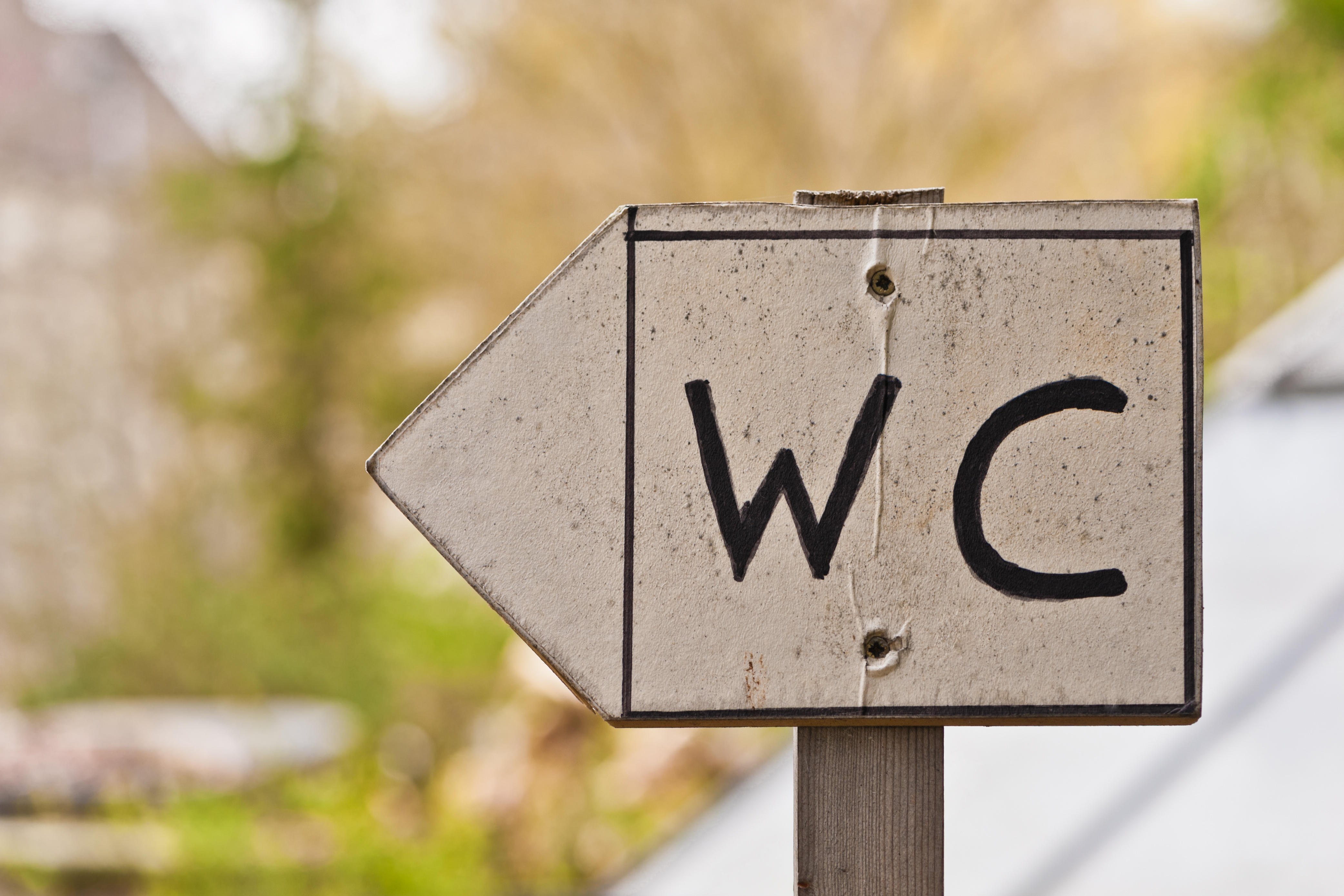 Handgemaltes WC-Schild aus Pappe an einer Holzleiste