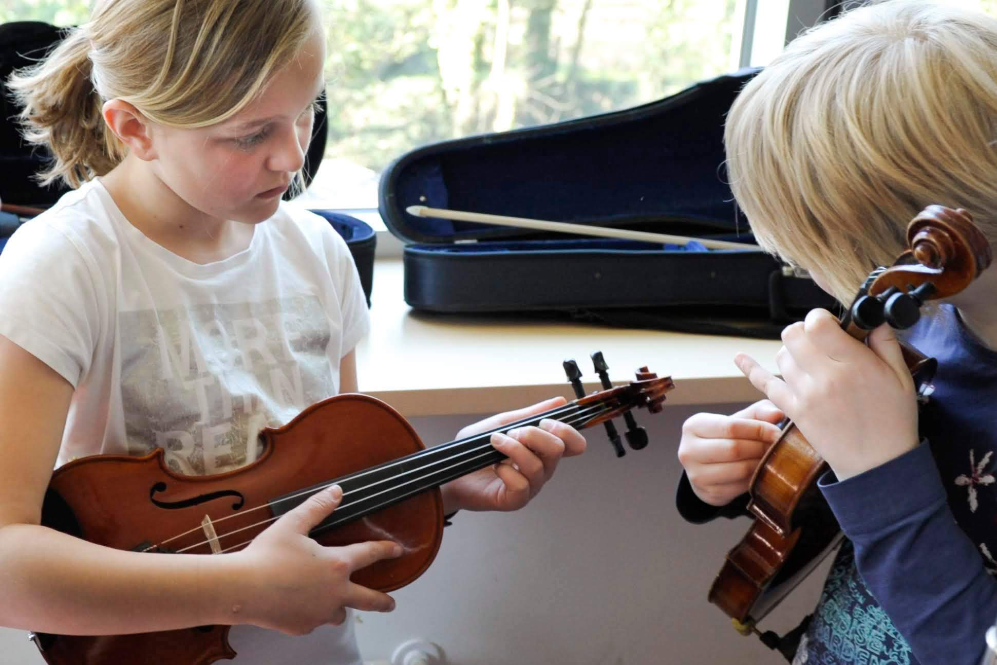 Zwei Kinder spielen Geige.