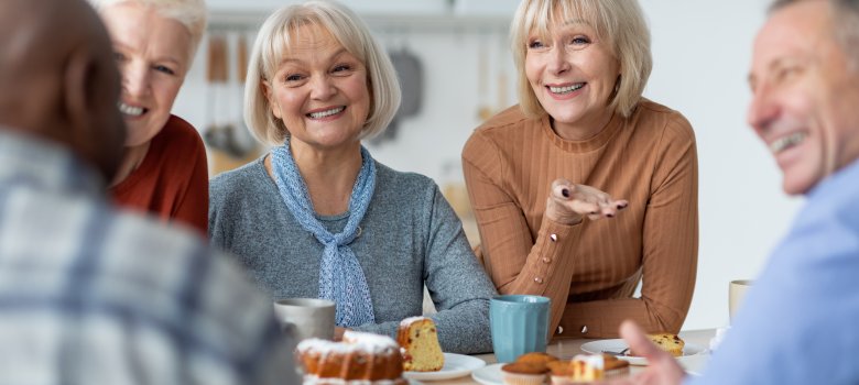Multiracial group of positive elderly people drinking tea with cake