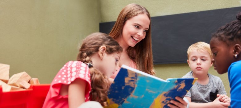 Symbolfoto Frau liest Kindern aus einem Buch vor