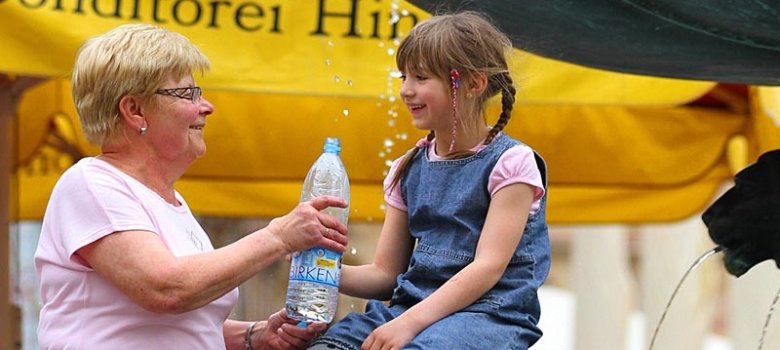Projekttitelbild: Oma reicht Kind Trinkwasser